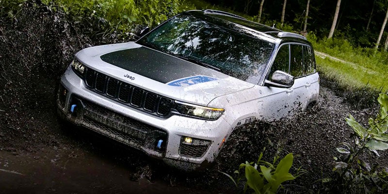 Image of the 2024 Jeep Grand Cherokee 4xe driving through muddy terrain to showcase its off-road capabilities