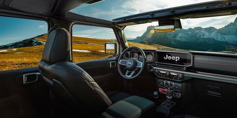 Image featuring the interior of a 2024 Jeep Grand Cherokee, with the moonroof open and a mountainscape seen through the windows