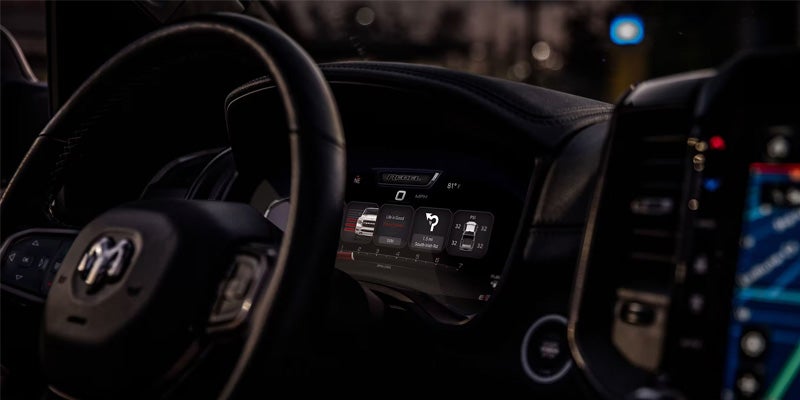 Image of the interior of the 2024 RAM 1500 featuring the steering wheel and the driver side dash mount illuminated