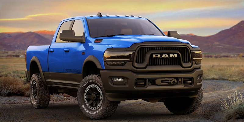 Image of the blue 2024 RAM 2500 facing toward the camera at an angle with a desert landscape as the backdrop