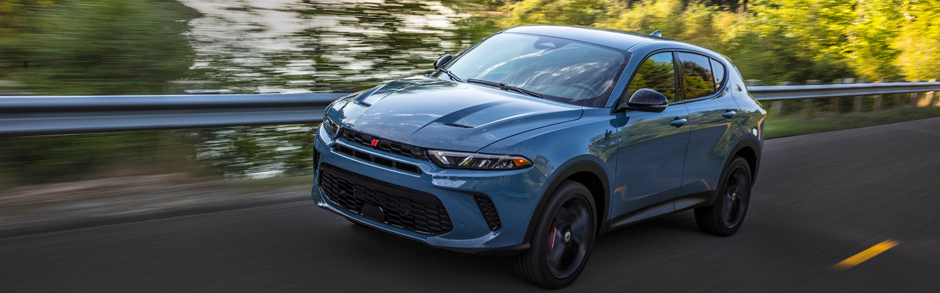 Image of the blue 2024 Dodge Hornet driving on a two-way bridge over a body of water