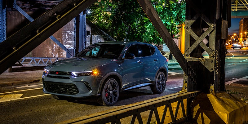 Image of the blue 2024 Dodge Hornet driving over a bridge in the city at night