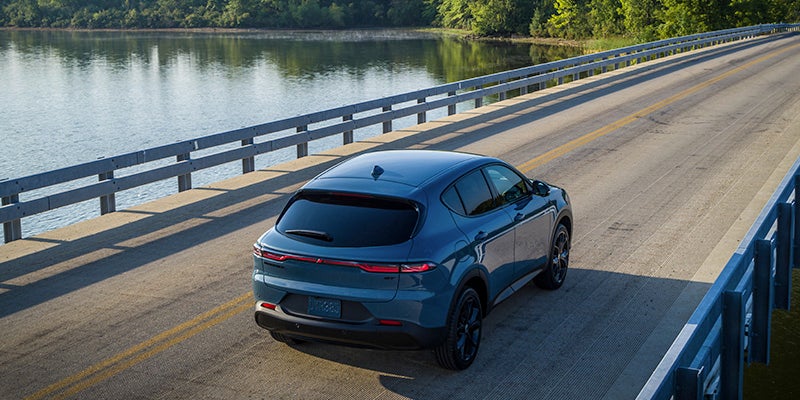 Image of the blue 2024 Dodge Hornet driving away from the camera on a bridge over a body of water