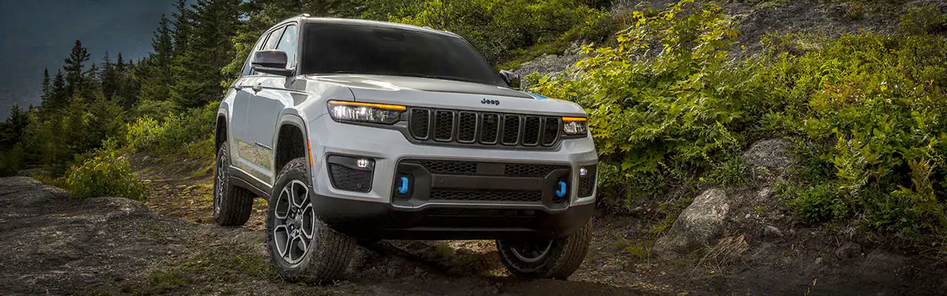 Image of the 2024 Jeep Grand Cherokee 4xe parked on rocky terrain in the mountains
