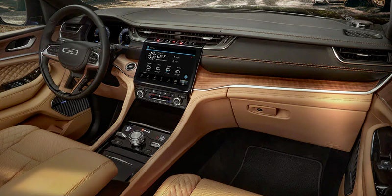 Interior image of the 2024 Jeep Grand Cherokee 4xe, showcasing brown leather and real wood detailing and infotainment system