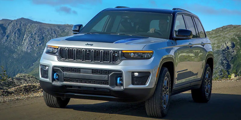 Image of the 2024 Jeep Grand Cherokee 4xe parked on a paved road in front of a mountainous landscape