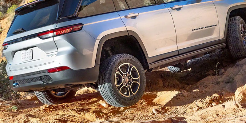 Detail shot of the 2024 Jeep Grand Cherokee 4xe driving at an incline on rocky terrain